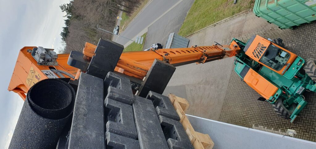 Cramer Manitou Teleskoplader beim Bauzaunfüsse auf Flachdach laden